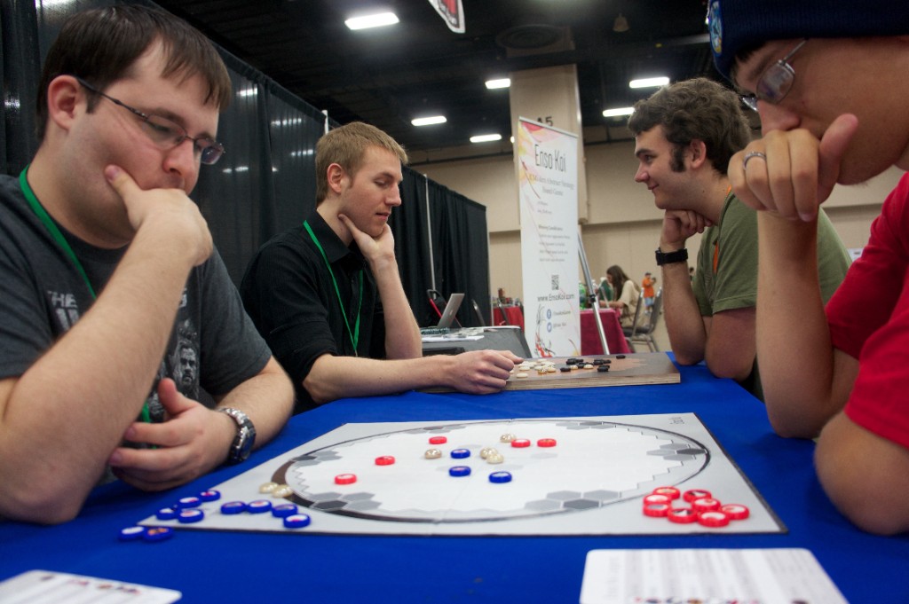 Four players focused on Enso Koi at a North Texas gaming convention, with the Enso Koi banner visible behind them.